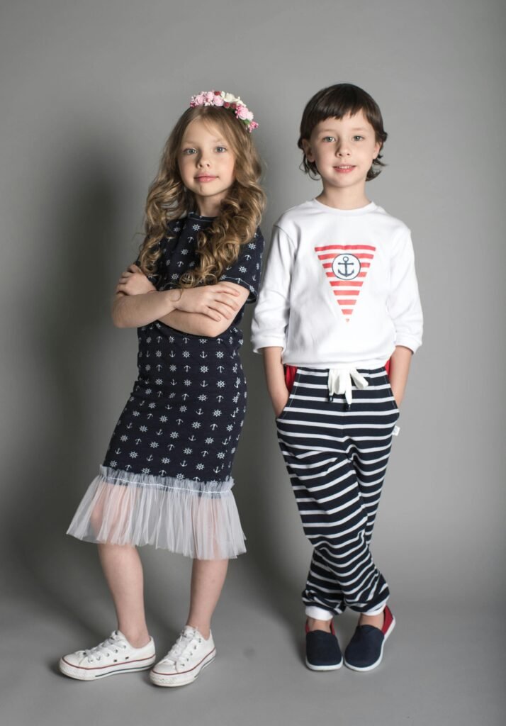 Girl in Black Dress Standing Beside Girl in White Sweatshirt and Black Striped Pants